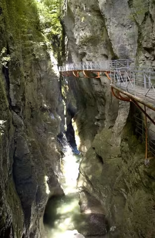 The footbridge fixed to the rock face, above the torrent, in the narrow gorge.